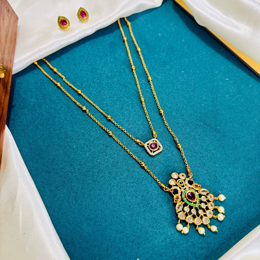 Elegant layered gold necklace with gemstone accents displayed on a teal fabric, representing Affordable Luxury jewelry collection by Poorni Fab.